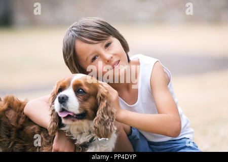 Beaugtiful les enfants d'âge préscolaire, jouer avec chien dans le parc, l'heure d'été Banque D'Images