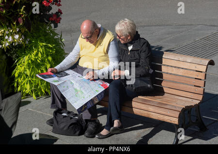 Couple de touristes senior consultant une carte tout en restant assis sur un banc dans la vieille ville, Montréal, QC, Canada Banque D'Images