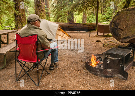 Senior adulte détente au feu de forêt, Sol Duc Campground, Olympic National Park, Washington State, USA Banque D'Images