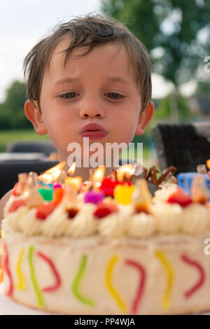 Quatre ans souffle les bougies sur son gâteau d'anniversaire Banque D'Images