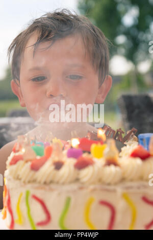 Quatre ans souffle les bougies sur son gâteau d'anniversaire Banque D'Images