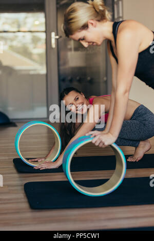 femme de fitness faisant de l'entraînement de pilates en utilisant une roue de yoga ou de pilates. Femme en position push up reposant les mains sur la roue de pilates. Banque D'Images