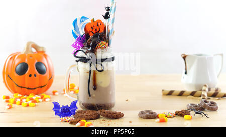 Sur-tendance Happy Halloween theme freak secoue les milk-shakes au chocolat décoré avec des bonbons, biscuits et sucettes. Banque D'Images