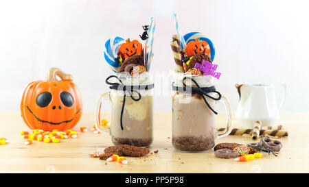 Sur-tendance Happy Halloween theme freak secoue les milk-shakes au chocolat décoré avec des bonbons, biscuits et sucettes. Banque D'Images