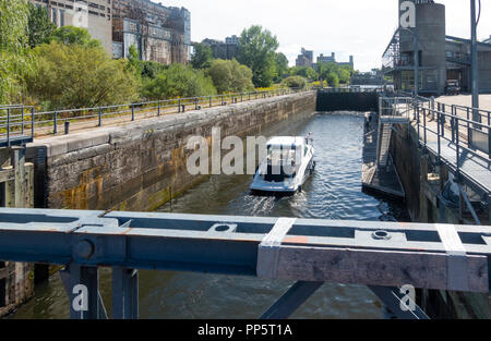 Un petit bateau de plaisance avec une femme et jeune garçon à bord navigation dans le canal de Lachine dans le Vieux Port de Montréal Banque D'Images