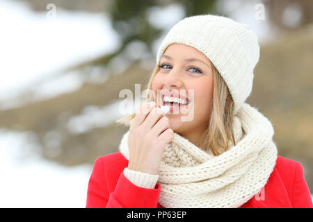 Femme heureuse application de baume à l'extérieur en hiver dans la montagne enneigée Banque D'Images