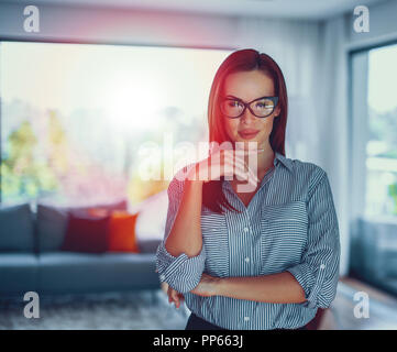 Young woman posing nerd moderne confiante dans la salle de séjour à l'intérieur dans le coucher du soleil Banque D'Images