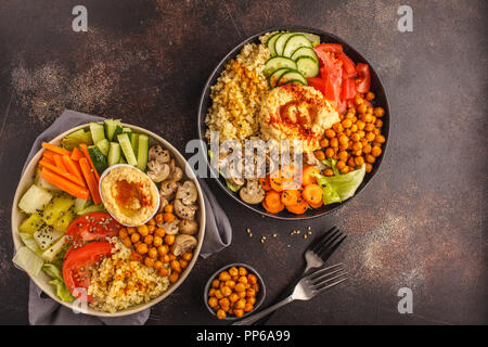 Bols de Bouddha avec des légumes, champignons, boulgour, pois chiches cuits et l'hummus. Fond sombre, vue du dessus. La nourriture végétalienne saine concept. Banque D'Images