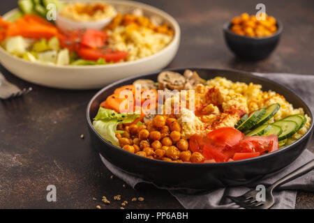 Bols de Bouddha avec des légumes, champignons, boulgour, pois chiches cuits et l'hummus. Fond sombre.Healthy vegan food concept. Banque D'Images