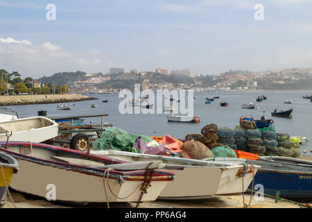 Porto, Portugal. Petits bateaux et matériel de pêche sur le quai et petits bateaux amarrés dans la baie avec la ville de Porto, Portugal en arrière-plan. Banque D'Images