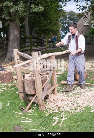 Carpenter en utilisant drawknife et cheval de rasage pour faire un poteau de clôture en chêne, Beamish Museum, Co Durham, England, UK Banque D'Images