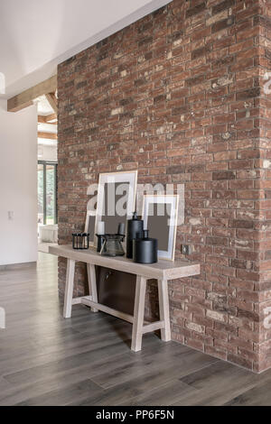 Située dans un style moderne avec du blanc et des murs de briques, poutres apparentes, parquet à l'étage. Il y a une table lumineuse avec différents Vases et chandeliers. V Banque D'Images
