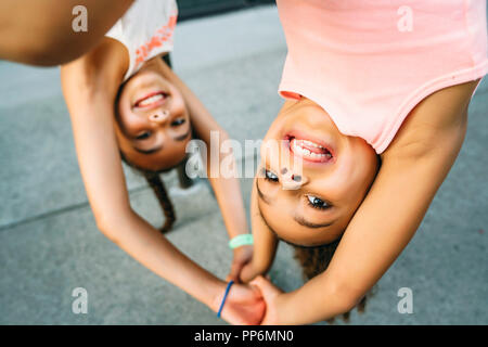 Happy smiling girls, suspendu à la barre de support à vélos sur le trottoir Banque D'Images