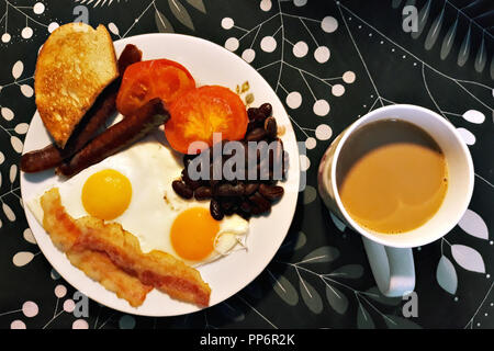 Plaque avec petit-déjeuner composé d'œufs brouillés, jambon, saucisses et haricots et à proximité d'une tasse de café aromatique avec eau chaude. Banque D'Images