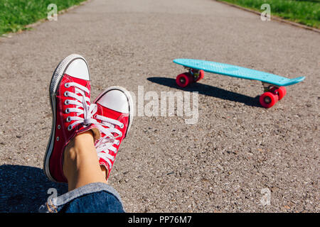 Close up de pieds d'une fille en rouge et bleu chaussures de skate board penny en plastique rose avec des roues sur l'arrière-plan. Scène urbaine, la vie en ville. Sport, cent Banque D'Images