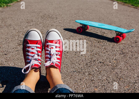 Close up de pieds d'une fille en rouge et bleu chaussures de skate board penny en plastique rose avec des roues sur l'arrière-plan. Scène urbaine, la vie en ville. Sport, cent Banque D'Images