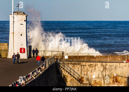 Violation des vagues le mur du port et sur le phare blanc comme les foules se rassemblent pour surveiller sur un après-midi ensoleillé à Largs, Northumberland, Angleterre. Septembre 2018. Banque D'Images