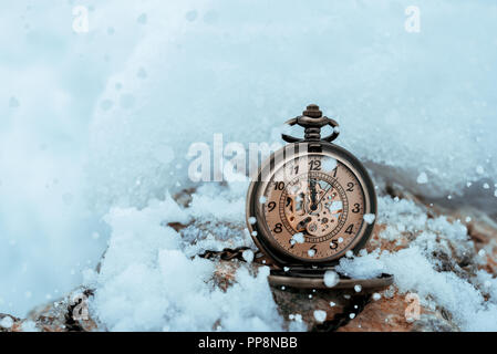 Nouvelle année réveil avant minuit. Montre de poche antique dans la neige Banque D'Images