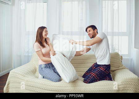 Couple in bed having fun lutter contre les oreillers dans la chambre Banque D'Images