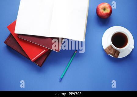 Fonds de l'étude. Arrière-plan de l'éducation. La papeterie. Aspects de l'éducation. La nourriture pour le cerveau. Crayon, ordinateur portable ouvert, des livres, une pomme, café et chocolat sur Banque D'Images