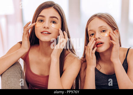 De belles petites femelles mettre les patchs sur beauté Visage Banque D'Images