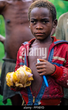 De l'enfant pygmée avec stylet et Scaff de touristes , sur le chemin de l'école, Bundibugyo, l'Ouganda, l'Afrique. Banque D'Images