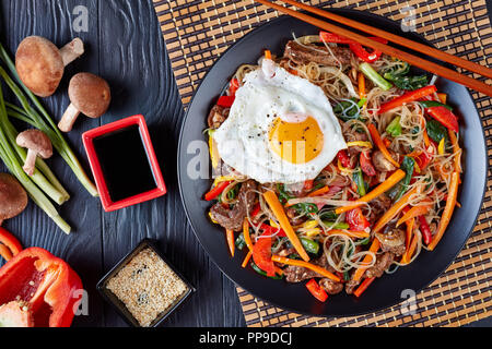 Japchae coréen sucré et salé : nouilles cellophane gonflable avec un mélange de légumes croquants : épinards, poivron rouge, oignon, carotte, l'ail, shiitake m Banque D'Images