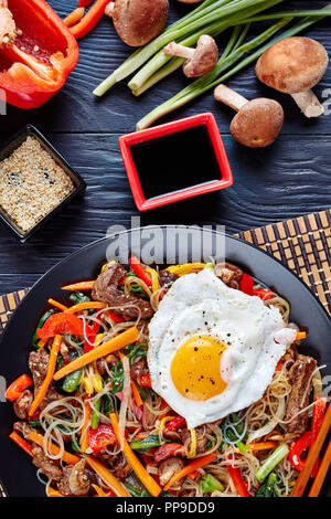 Japchae coréen ou chapchae nouilles de fécule de pomme de terre douce, dangmyeon, boeuf et légumes divers, les champignons shiitake, œuf frit sur le dessus avec une sauce de soja Banque D'Images