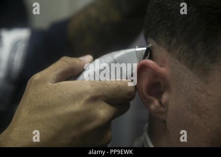 Lance le Cpl. Andrew J. Thompson, un linguiste de chiffrement avec la 31e Marine Expeditionary Unit, obtient une coupe au salon de coiffure pour hommes à bord du navire d'assaut amphibie USS Wasp LHD (1) installation navale à White Beach, Okinawa, Japon, le 17 août, 2018. Thompson, originaire de Pearland, Texas, est diplômé de l'école secondaire de Pearland en juin 2014 avant de s'enrôler dans le Corps des marines en mars 2015. 31e MEU Marines et marins se couper les cheveux à la coiffure en bateau pour faire face à une réglementation uniforme en tout temps. La 31e MEU, le Marine Corps' seulement continuellement de l'avant-déployés MEU, fournit une force flexible Banque D'Images