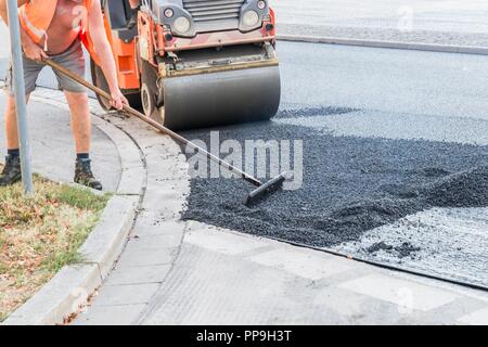 Les travailleurs de la route d'asphalte chaud se propager avec des pelles et roulant sur la route, Allemagne Banque D'Images