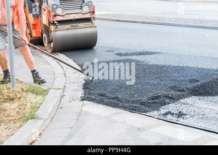 Les travailleurs de la route d'asphalte chaud se propager avec des pelles et roulant sur la route, Allemagne Banque D'Images