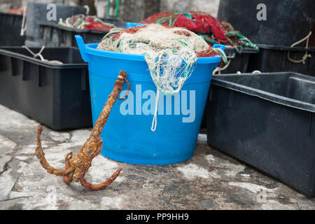 Village de pêcheurs méditerranéen quai avec tambours et les conteneurs remplis de filets de pêche sur le quai de près. Banque D'Images