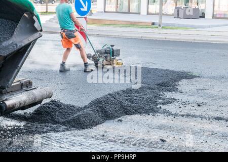 Les travailleurs de la route d'asphalte compact avec un pilon vibrant sur la route, Allemagne Banque D'Images