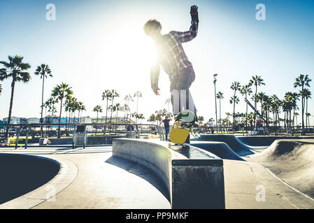 Cool skateboarder plein air - Afroamerican guy jumping avec son skate et de faire un truc Banque D'Images