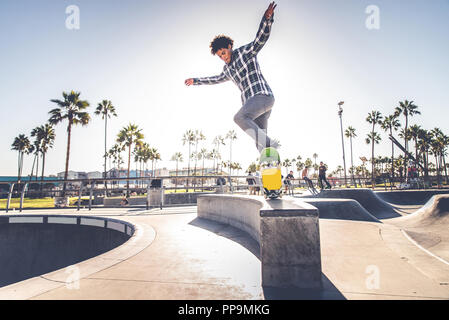 Cool skateboarder plein air - Afroamerican guy jumping avec son skate et de faire un truc Banque D'Images