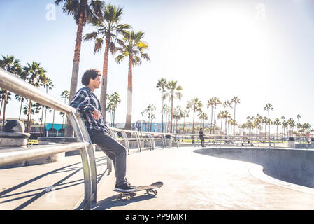 Cool skateboarder plein air - Afroamerican guy jumping avec son skate et de faire un truc Banque D'Images