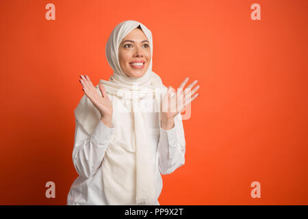 Heureux surpris femme arabe en hijab. Portrait of smiling girl, posant au red studio arrière-plan. Jeune femme émotionnelle. Les émotions humaines, l'expression faciale concept. Vue de face. Banque D'Images