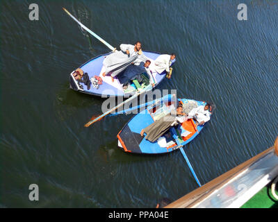 Hommes égyptiens dans leurs petites embarcations s'efforcent d'attirer l'attention des passagers sur un bateau de croisière afin d'essayer de leur vendre des tapis, serviettes, nappes et autres marchandises sur le Nil en Egypte. Banque D'Images