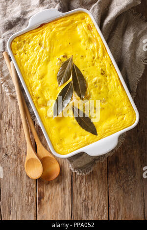 Bobotie sud africain épicé plat composé de viande hachée cuite au four avec un oeuf en fonction de la garniture dans un plat allant au four, sur la table. Vue supérieure verticale Banque D'Images