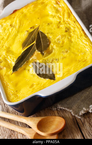 Cocotte Bobotie sud-africaines traditionnelles à la viande hachée épicée recouverte d'omelette close-up dans un plat allant au four, sur la table verticale. Banque D'Images