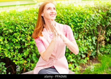 Belle jeune fille assise sur un banc en bois à l'air libre se réjouit. Journée ensoleillée buissons verts vie focus sélectif copy space Banque D'Images