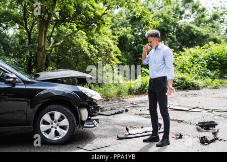 Couple par la voiture, faire un appel téléphonique après un accident de voiture. Banque D'Images