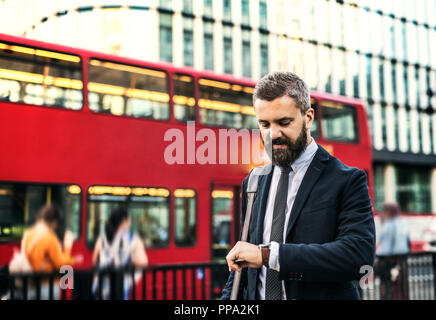 Homme d'Hipster en attendant le bus à Londres, contrôle du temps. Banque D'Images