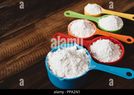 Tasses à mesurer colorés avec de la farine sur la table en bois. Concept de la cuisine et outils de cuisine Banque D'Images