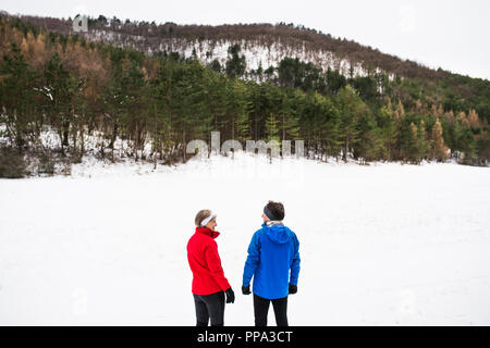 Senior couple porteur debout dans la nature, le repos d'hiver. Banque D'Images