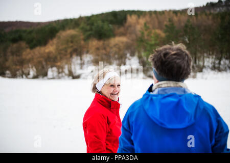 Senior couple porteur debout dans la nature, le repos d'hiver. Banque D'Images