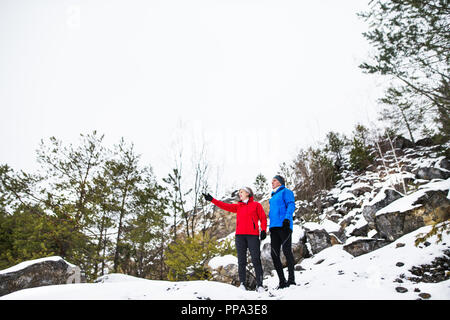 Senior couple porteur debout dans la nature, le repos d'hiver. Banque D'Images