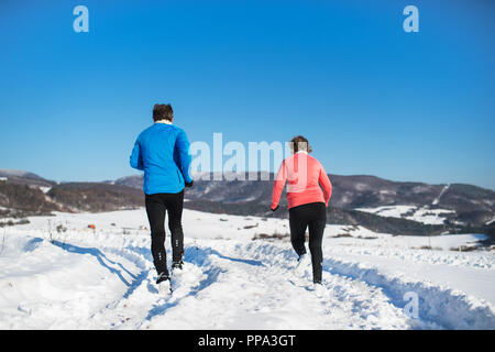 Vue arrière de la haute couple jogging en hiver la nature. Banque D'Images