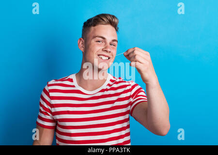 Portrait d'un jeune homme dans un studio, tirant un chewing-gum. Banque D'Images