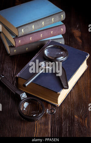 Vintage Books et loupe, sur fond de bois Banque D'Images